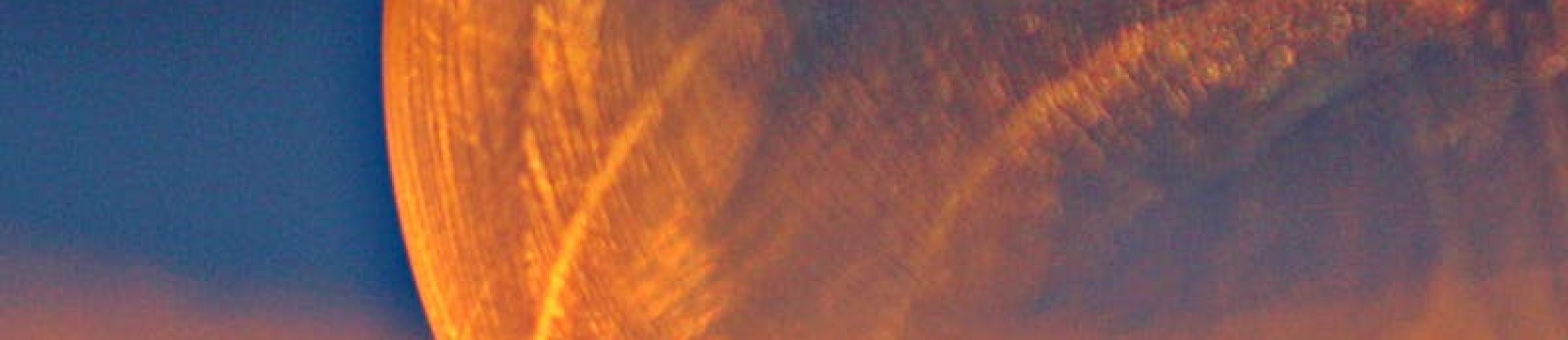 Close-up shot of a frozen bubble with warm reflections resting on a snowy surface at twilight.